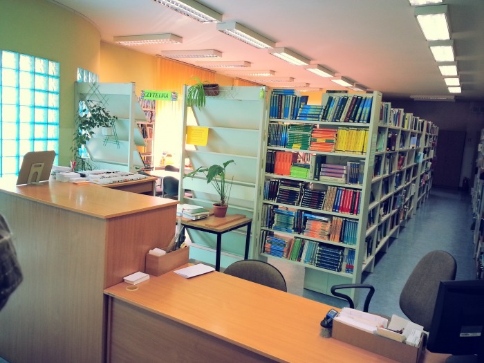 Zdjęcie zrobione w bibliotece Filii uł przedstawia stanowisko obsługi studenta z regałami z kksiążkami w tle