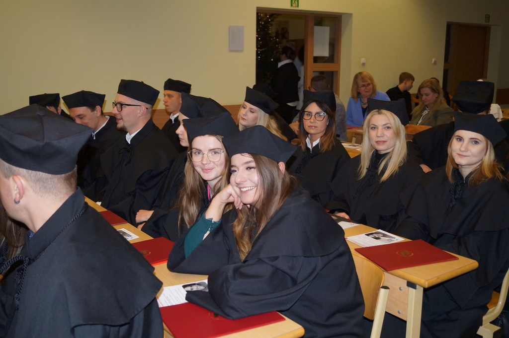 absolwenci siedzący w ławach na auli