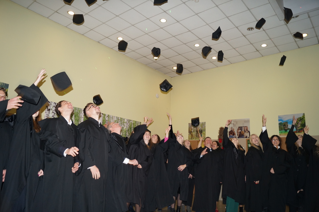 absolwenci podrzucający birety na patio w filii uł