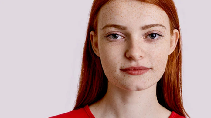 Piegowata ruda studentka na jasnym tle