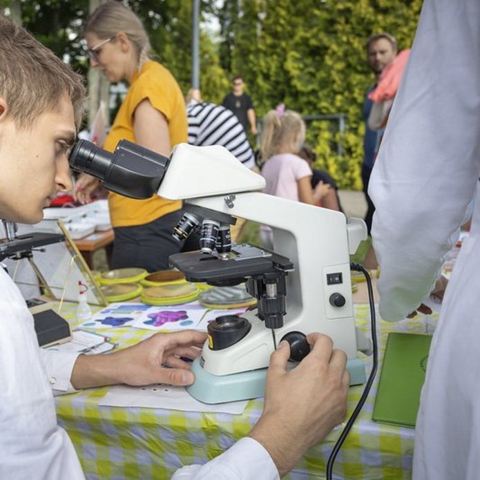 młody człowiek nachyla się nad okularem mikroskopu 