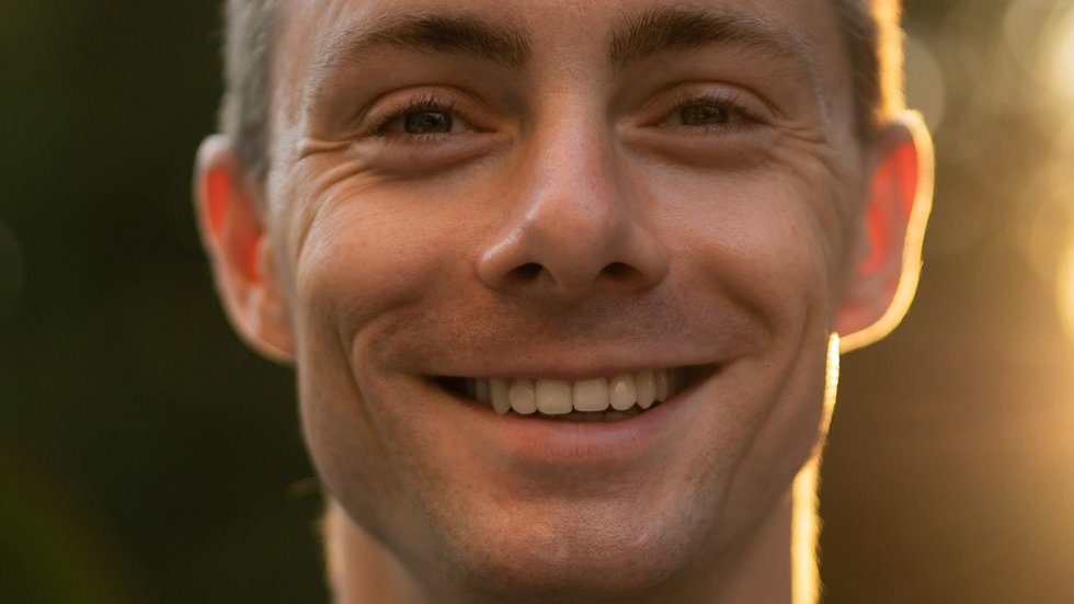 Uśmiechnięty młody mężczyzna na tle drzew