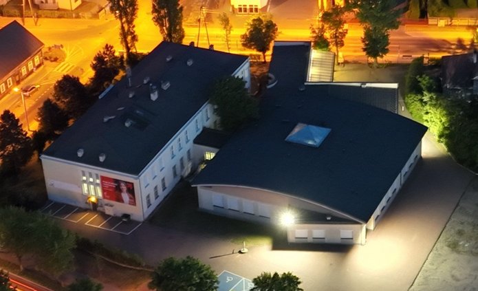 zdjęcie przedstawia budynek filii wraz z parkingiem i otaczającym go terenem zdjecie zrobione nocą z drona