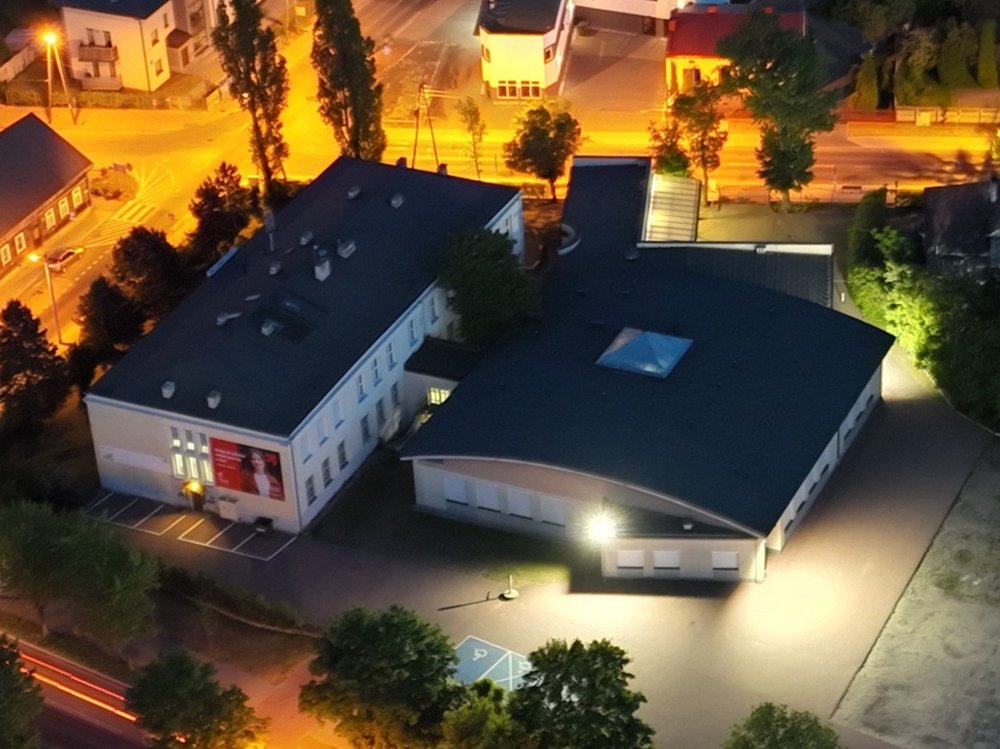 zdjęcie przedstawia budynek filii wraz z parkingiem i otaczającym go terenem zdjecie zrobione nocą z drona