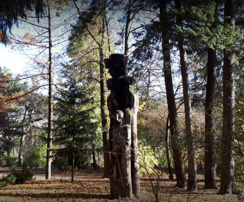 fotografia przedstawiajaca fragment ladu z pomnikiem wyrzezbionym z pnia drzewa