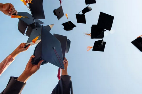 na zdjęciu widać czapki absolwentów podrzucone w górę na tle blękitnego nieba