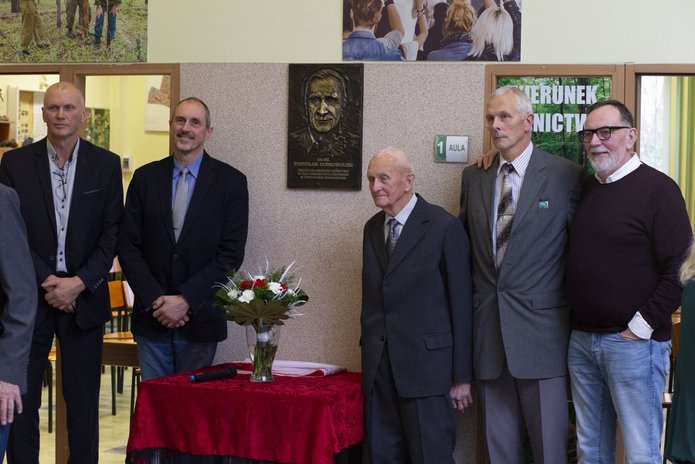 Zdjęcie braci i syna dr Dobrowolskiego pod tablica upamiętniajaca jego imię.