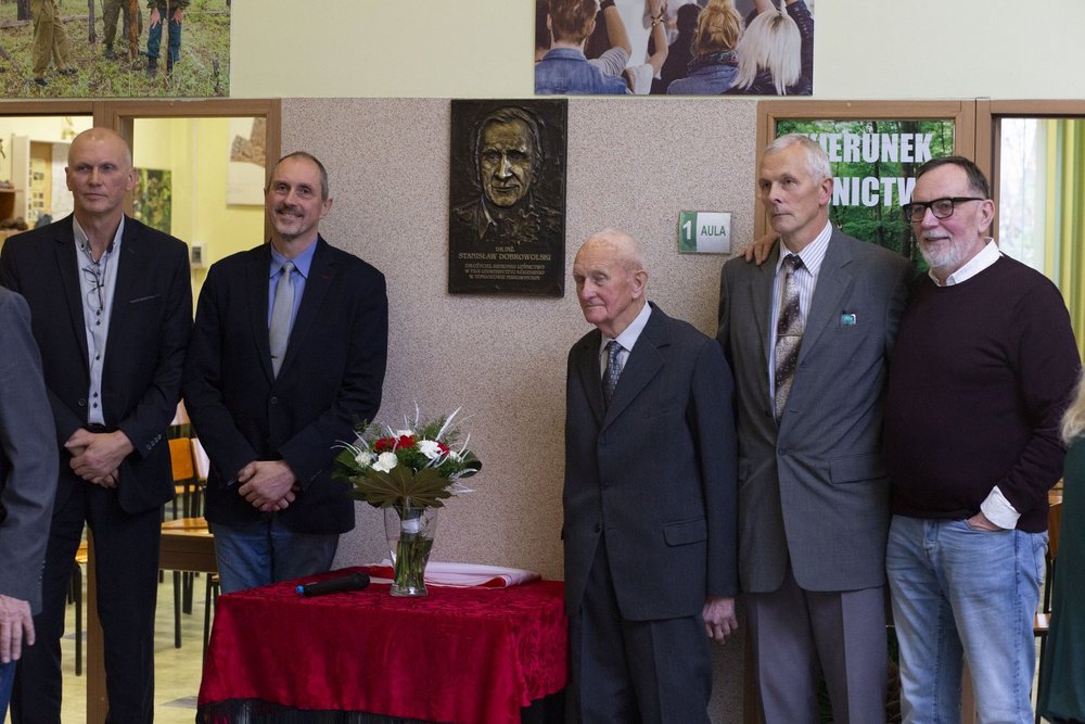 Zdjęcie braci i syna dr Dobrowolskiego pod tablica upamiętniajaca jego imię.